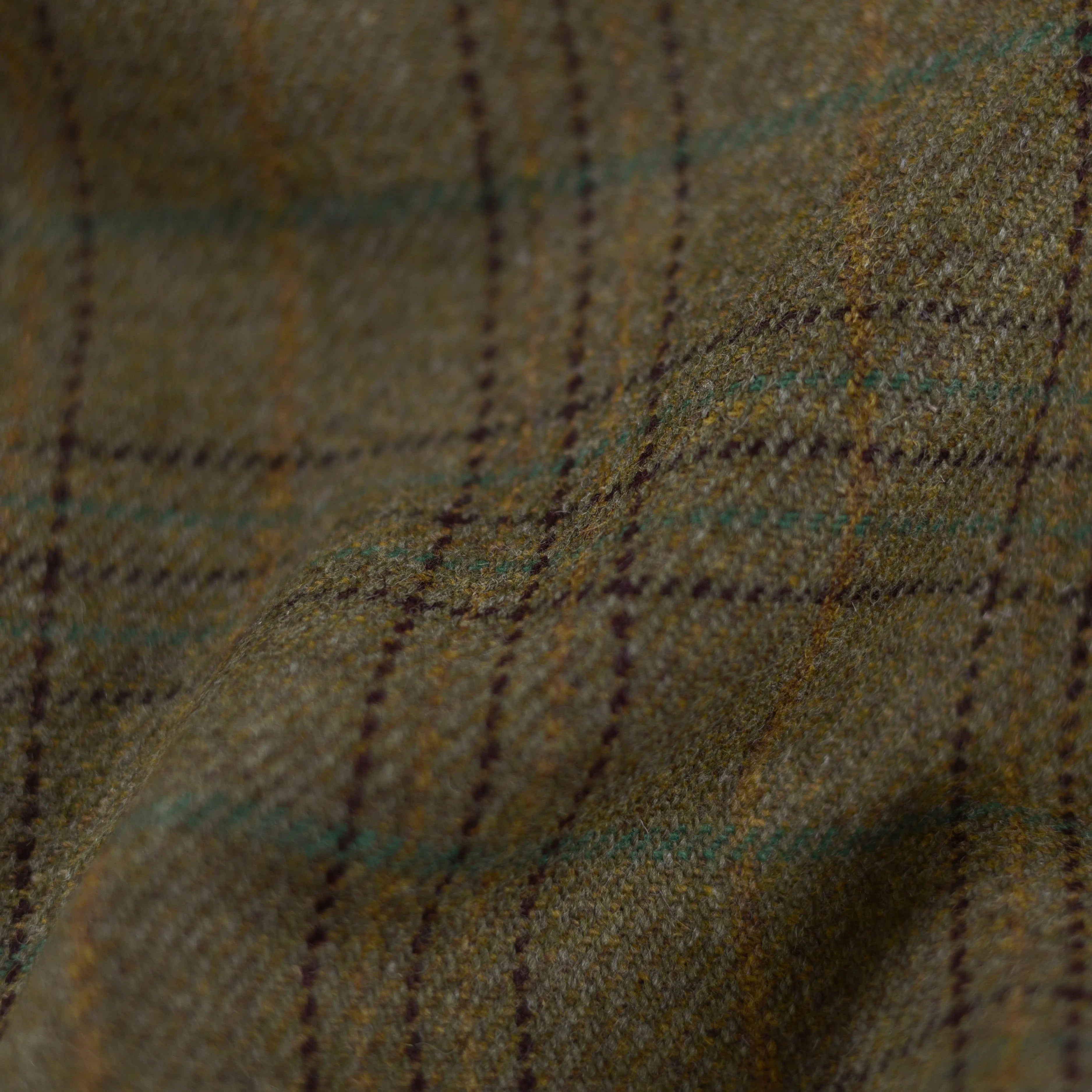 Close-up of House Tweed 30249 by Campbells of Beauly, a brown and green plaid wool fabric. Yellow and dark lines form a classic check typical of Scottish Estate Tweed, highlighting its rich texture and fine craftsmanship.