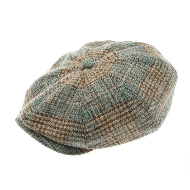 The Farrar Cap by Campbells of Beauly is a classic newsboy style in muted green and beige plaid, inspired by British country heritage, with a round button on top and a paneled design.