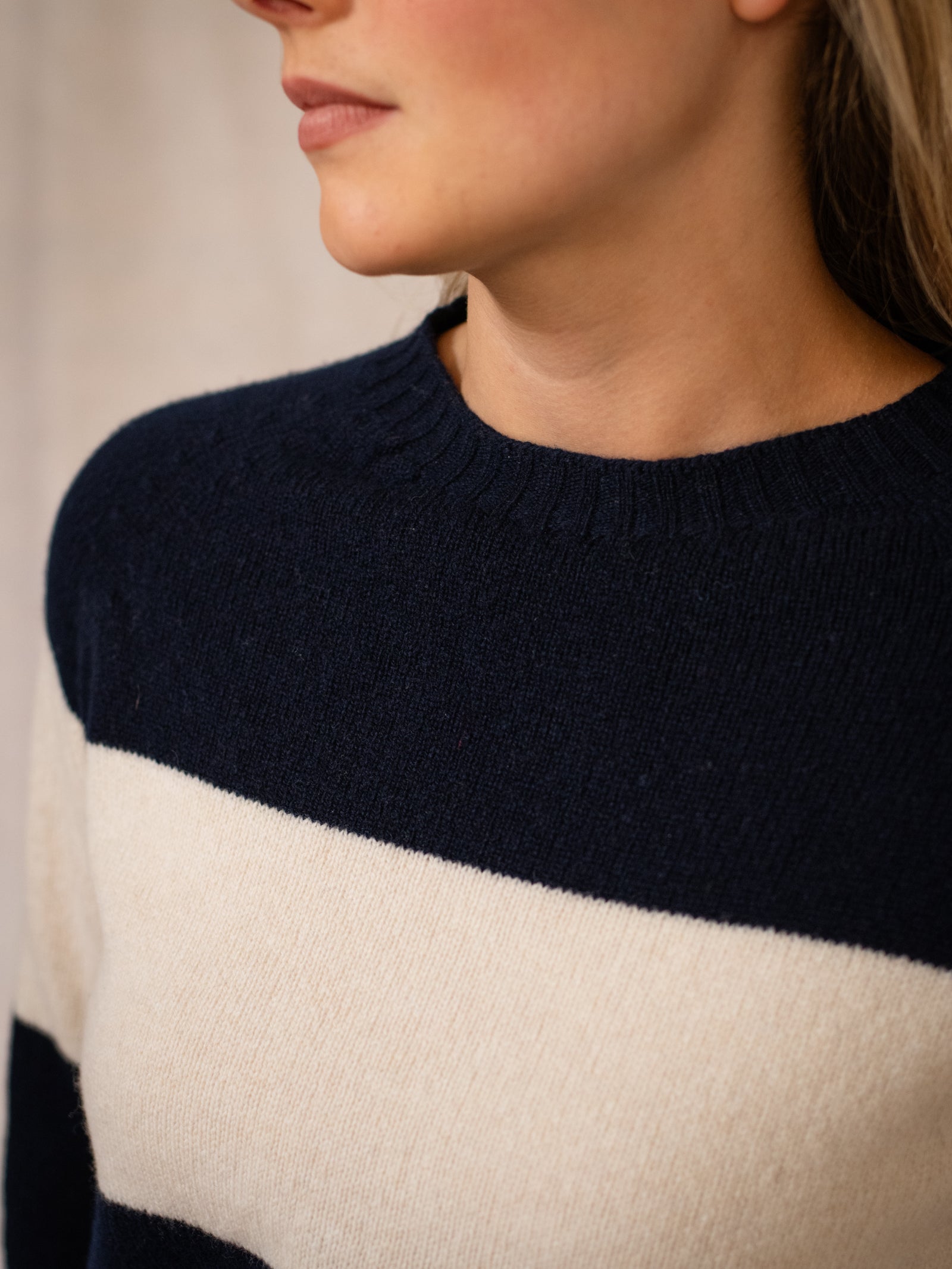 Close-up of a person wearing the Campbell's of Beauly Geelong Stripe Crew, featuring navy blue and white stripes. The relaxed fit and premium yarns are highlighted against a soft, neutral background, with hair partially visible.