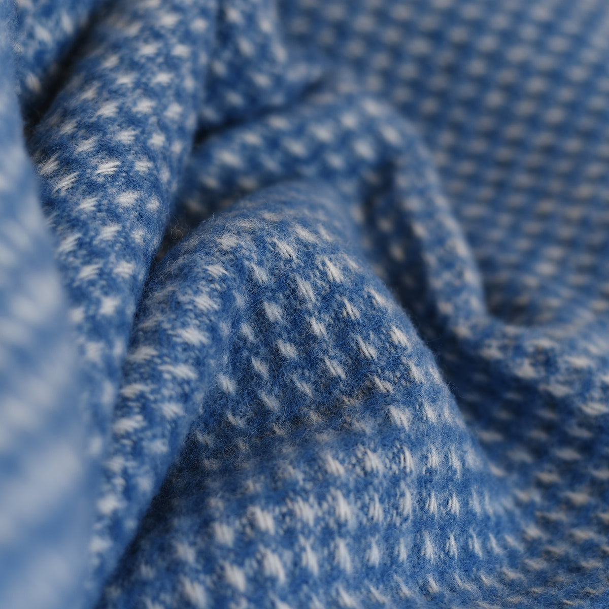 Close-up of the Honeycomb Lambswool Throw by Campbells of Beauly, showcasing its soft blue-and-white dots and subtle honeycomb weave—an inviting layer of warmth for your Yorkshire-inspired home.