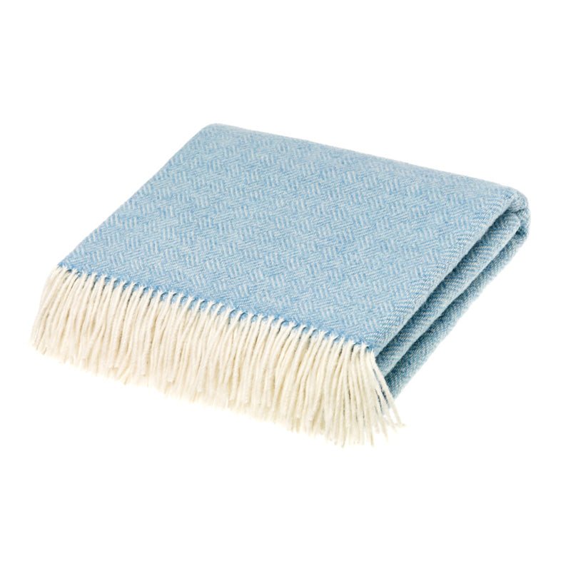 The Campbells of Beauly Parquet Lambswool Blanket in aqua features a subtle geometric parquet weave and a cream fringe along one edge, shown folded on a white background.
