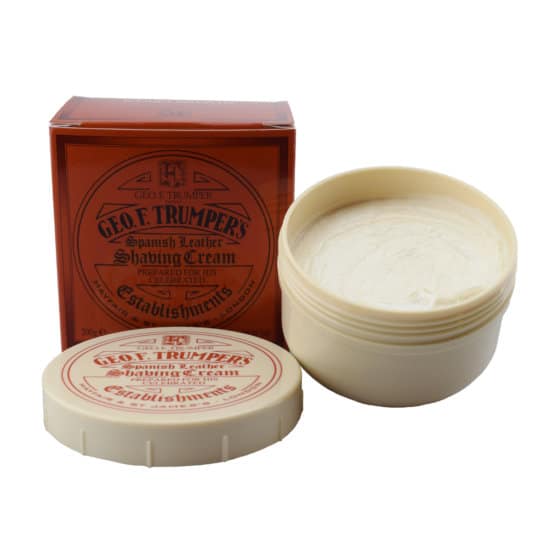 An open tub of Geo. F. Trumper Spanish Leather Shaving Cream reveals its rich contents beside the closed box, both clearly labeled with the brand and product name.
