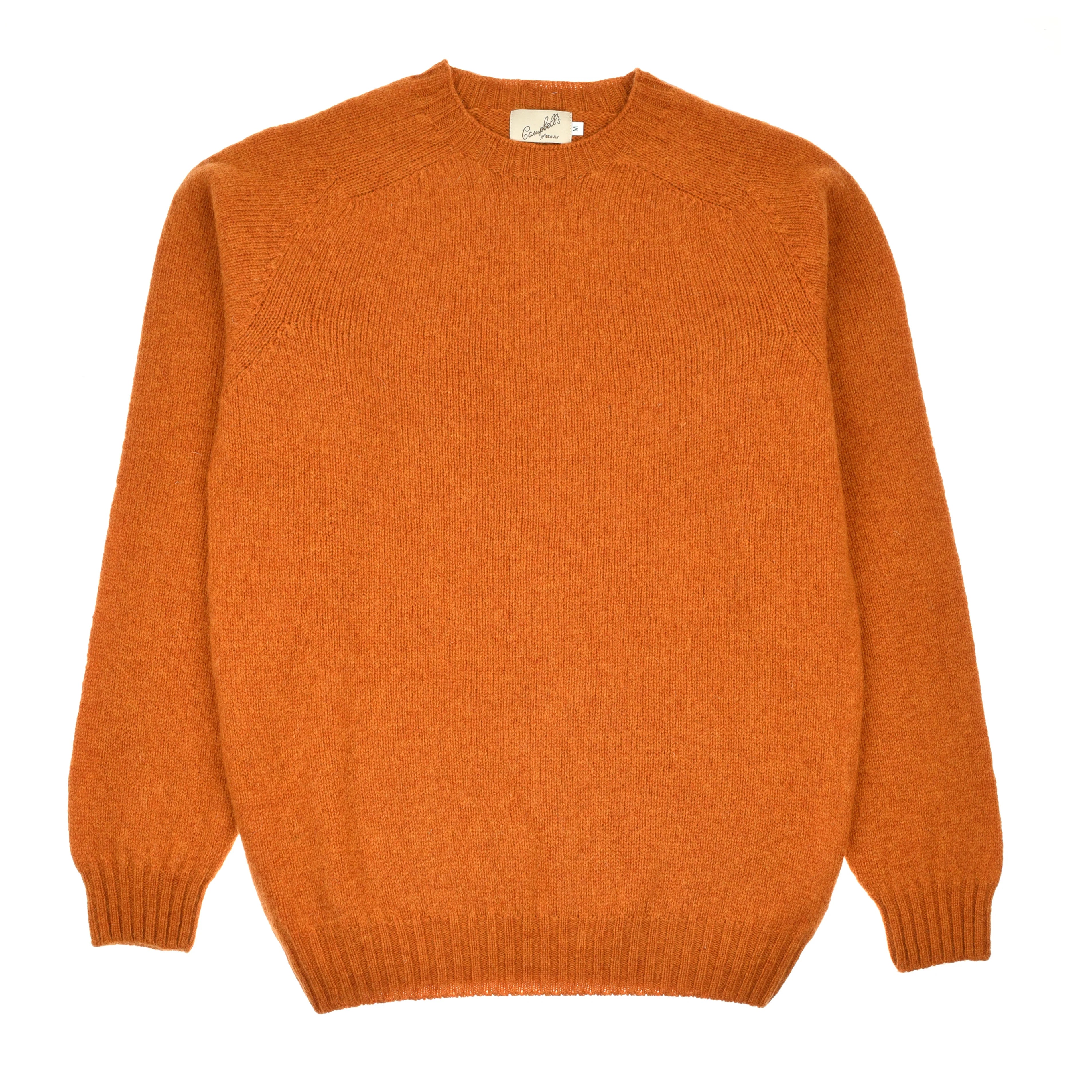 A Campbell's of Beauly Shetland Jumper in Autumn Leaf, a solid orange, long-sleeve crew-neck lambswool sweater, is laid flat on a white background.