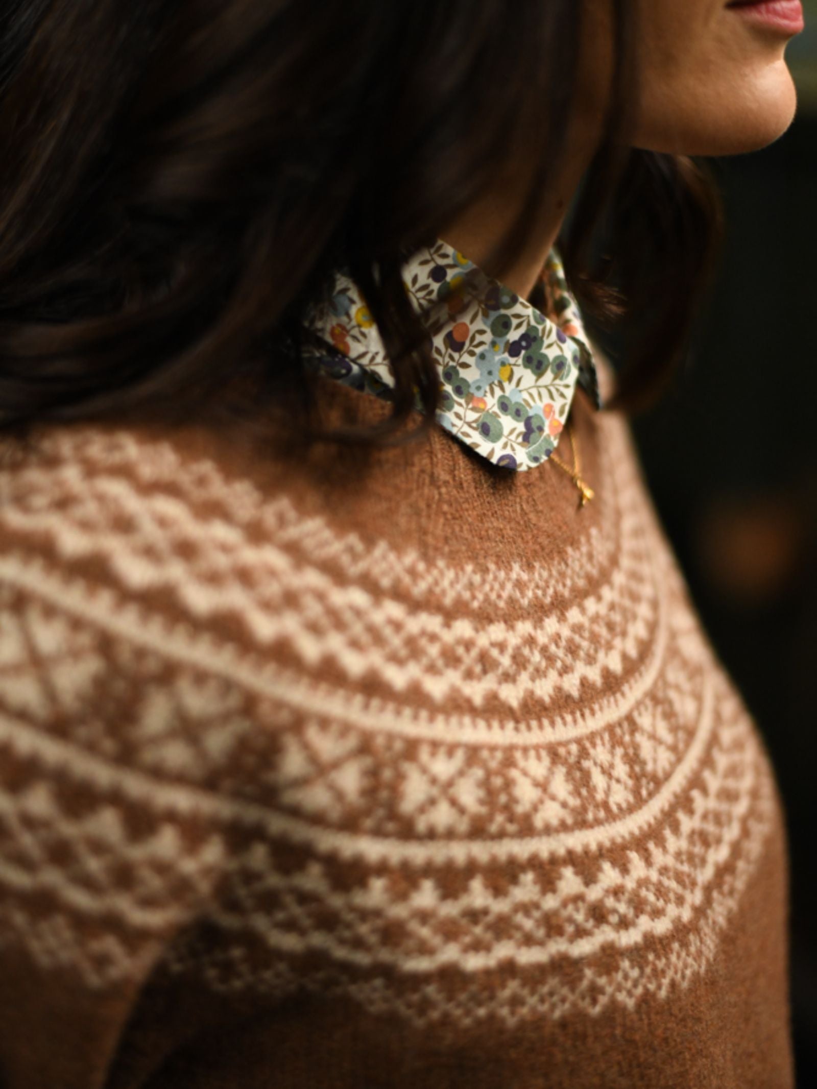 A person wearing the Campbell's of Beauly Two-Colour Fairisle Yoke Jumper over a floral print collared shirt, shown from the shoulders up with their face mostly out of frame.