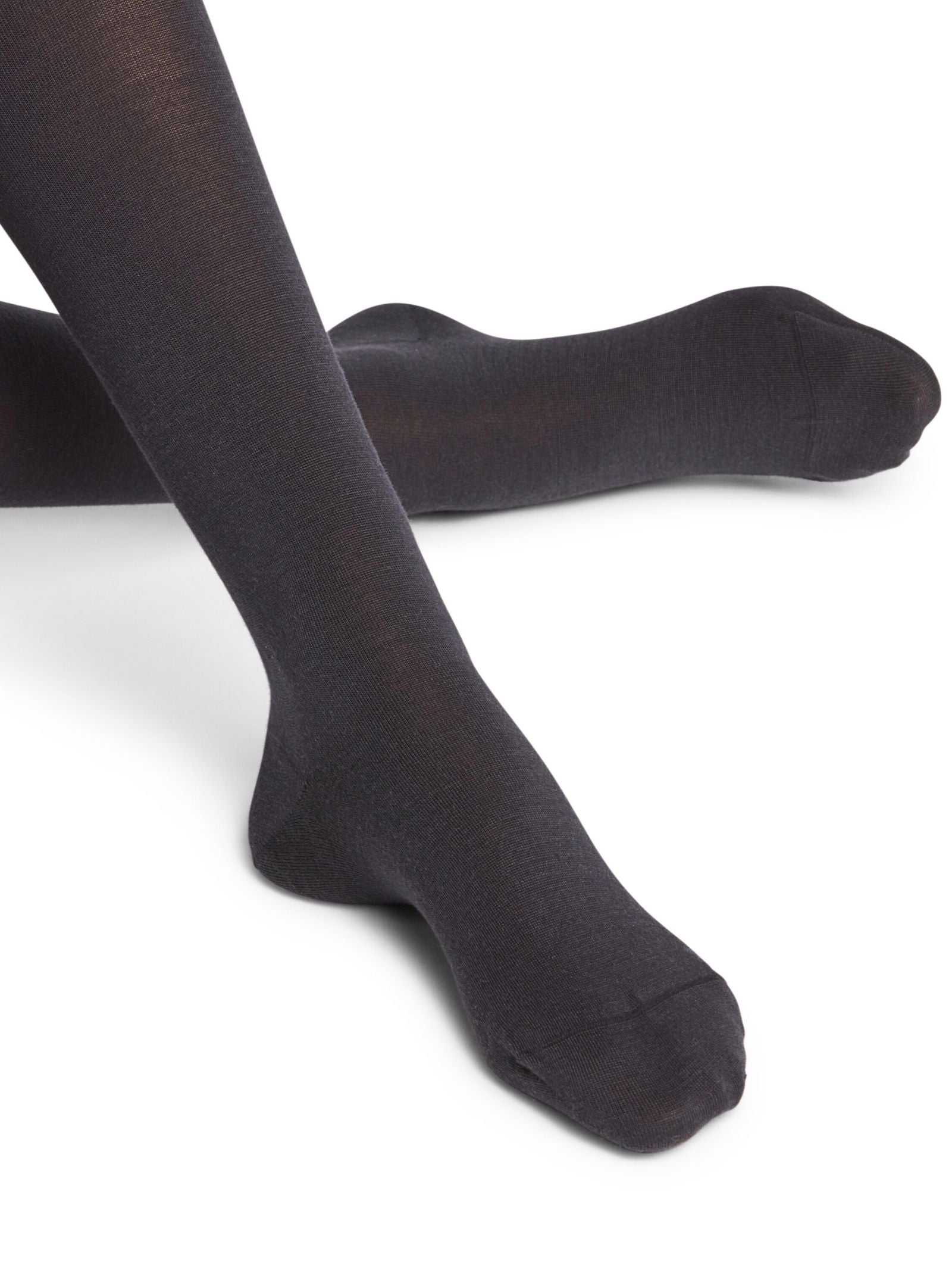 Close-up of two legs wearing FALKE Merino Tights in Dark Navy, with one leg bent and the other extended, shown against a white background.