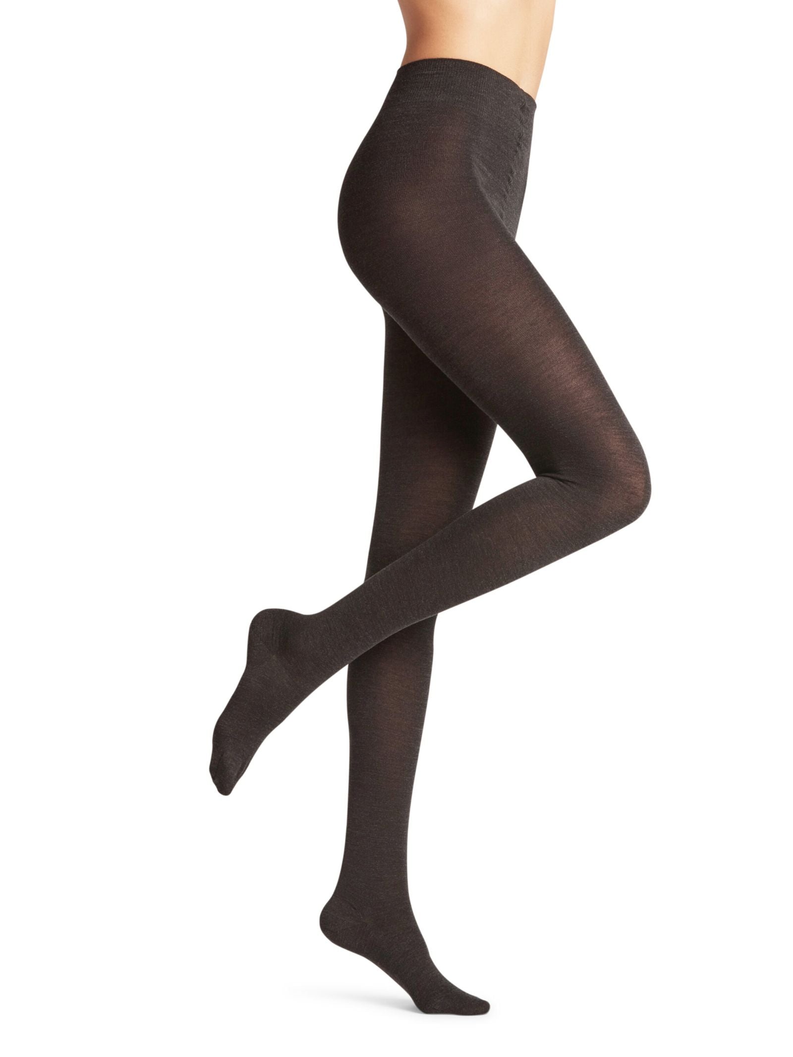 A person models FALKE Merino Tights in opaque black, standing on one leg with the other knee bent, set against a plain white background. The tights are shown from waist down; the upper body is not visible.