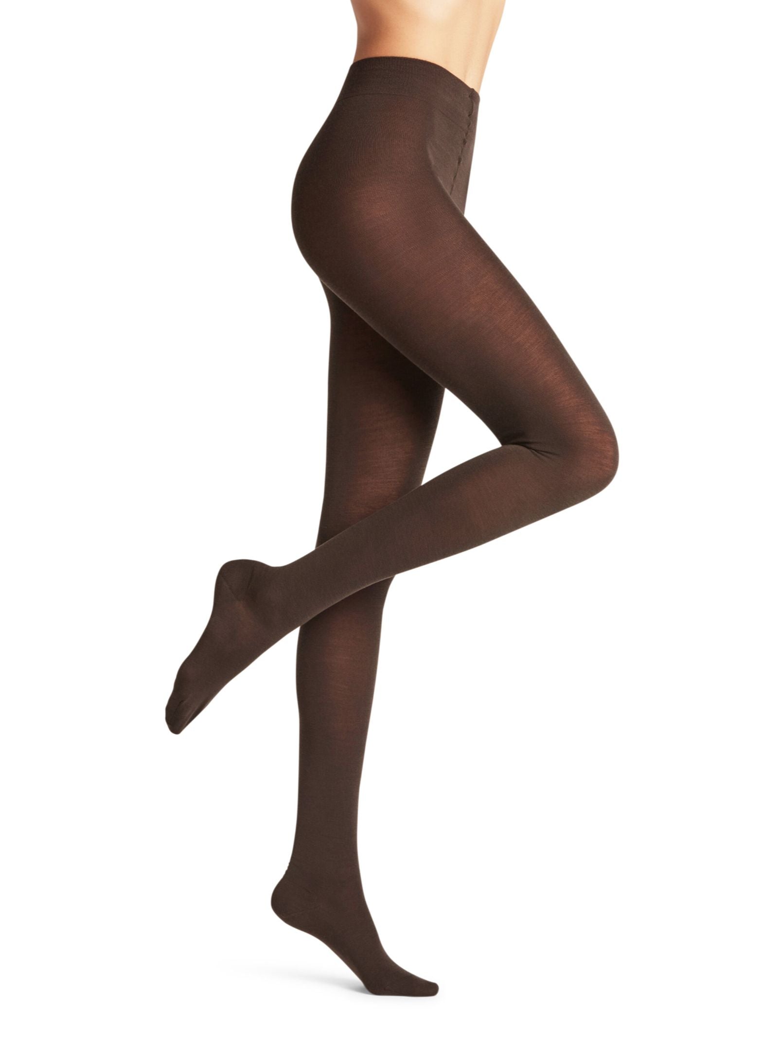 A person models FALKE Merino Tights in opaque brown, standing on one leg with the other knee bent, set against a white background. Only the lower body is visible.