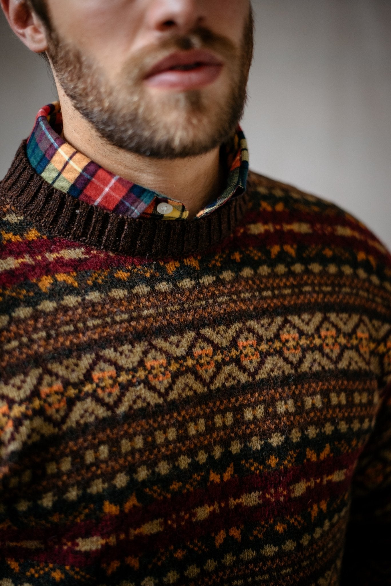 A close-up of a man in the Campbell's of Beauly Shetland Fairisle Crew Neck Jumper, showcasing rich Shetland wool patterns and textures—a timeless winter staple with his lower face and beard partially visible.