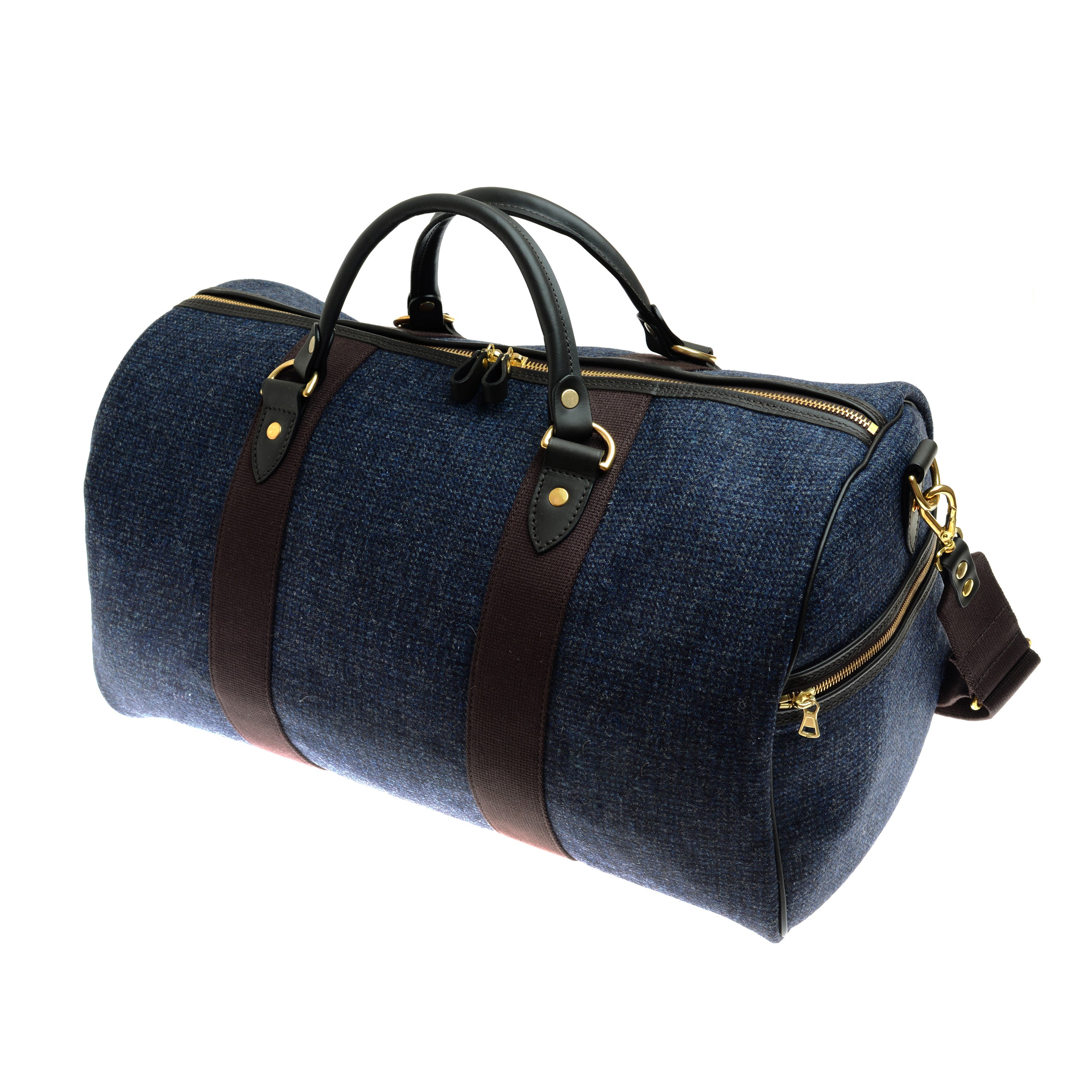 The Campbells of Beauly Hand Luggage Holdall is a spacious blue cylindrical bag with black bridle leather handles, gold zippers, and a brown shoulder strap—ideal for travel or gym use.