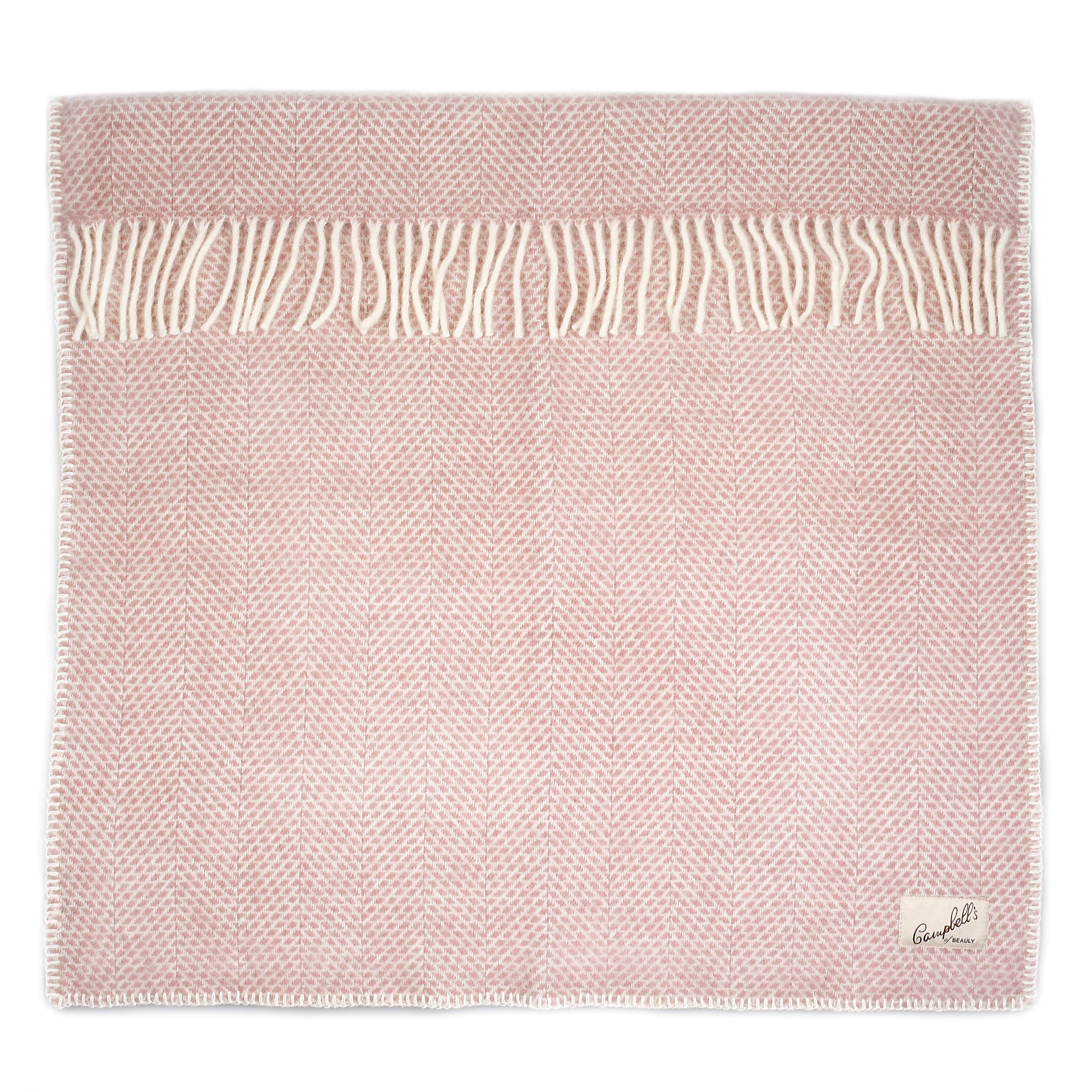 A softly pink Baby Blanket by Campbells of Beauly, crafted from wool with a breathable herringbone pattern, cream fringes on one edge, and a small brand label in the bottom right corner, is neatly folded against a white background.