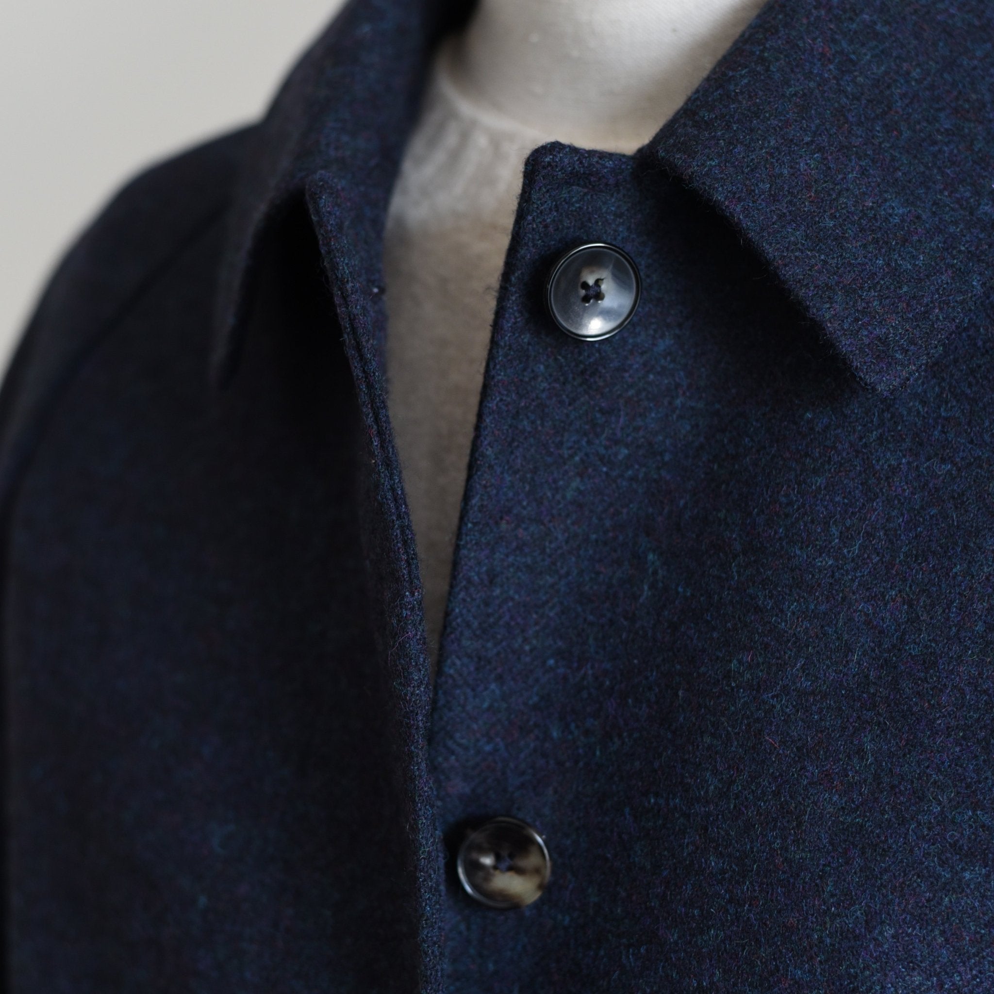 Close-up of the Campbells of Beauly Midnight Collar Coat, showing classic tailoring, textured dark wool fabric, two visible buttons, and collar details over a light knit garment.