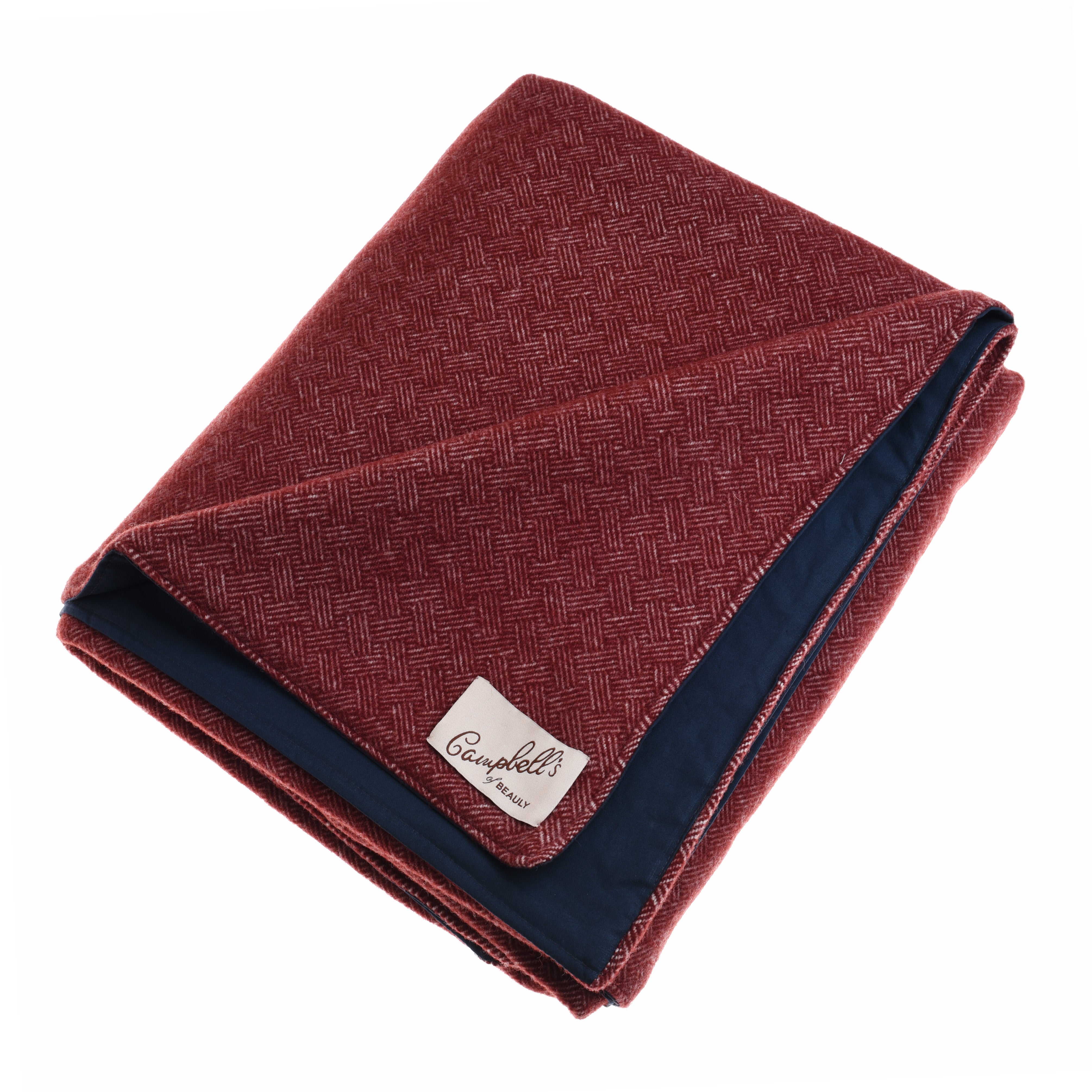 A folded red Waterproof Picnic Blanket by Campbell’s of Beauly features a subtle herringbone pattern, navy underside, and a white label. Showcasing heritage weaving, the blanket is neatly arranged against a plain white background.