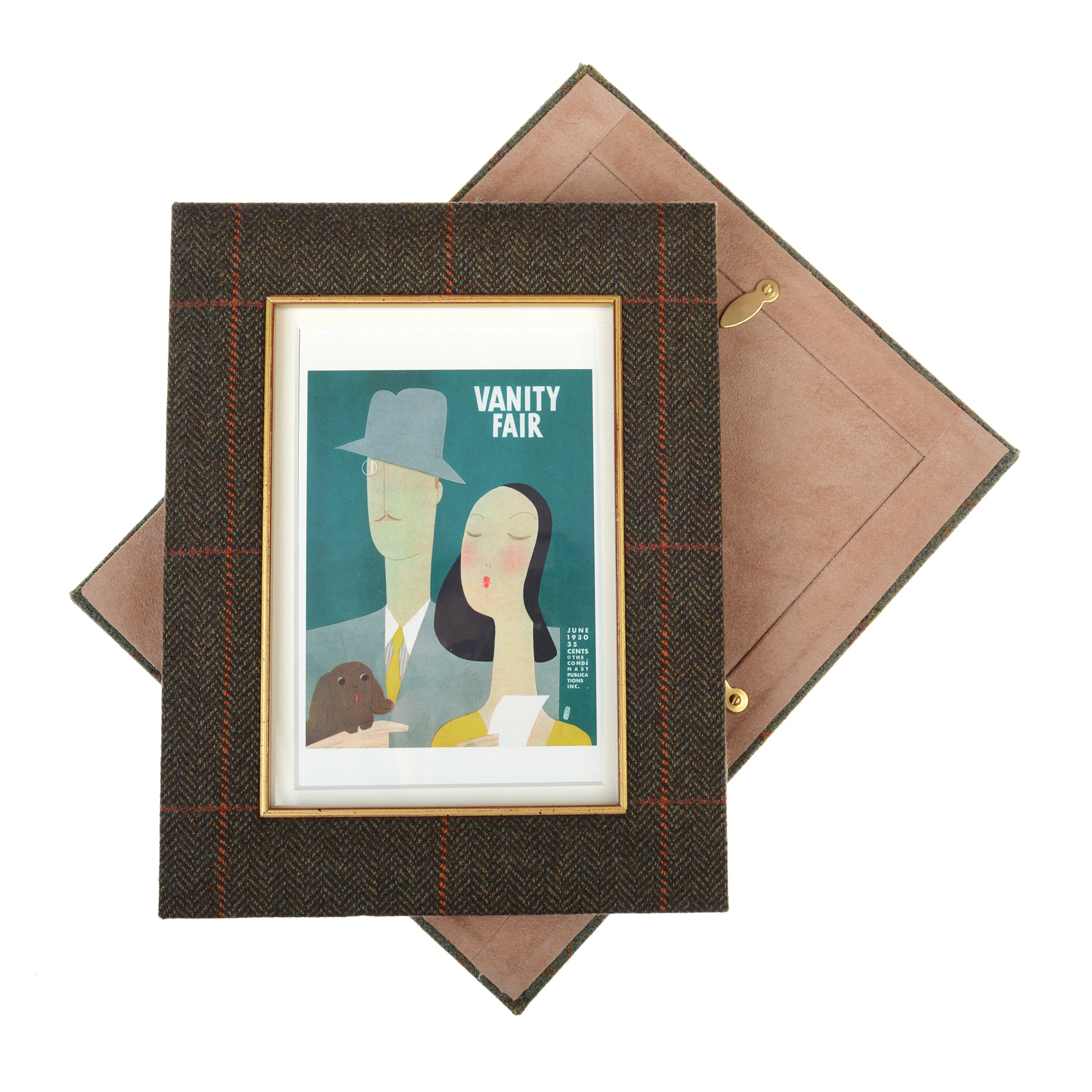 The Campbells of Beauly Tweed Photoframe, featuring brown plaid tweed and a gold inner border, displays a stylized Vanity Fair illustration. The frame sits angled on an open tan suede box.