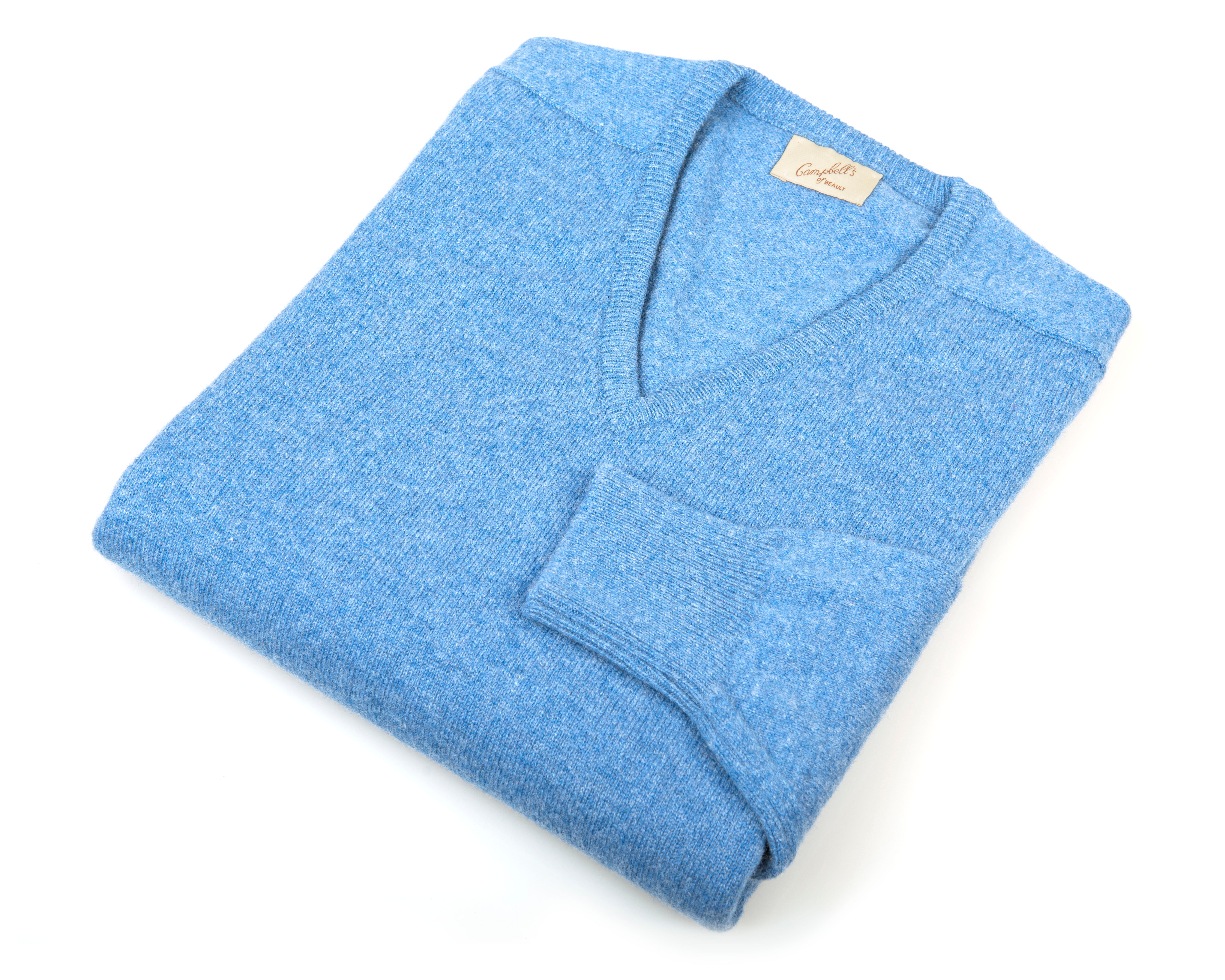A light blue Campbells of Beauly Lambswool V-Neck Jumper in classic fit is neatly folded on a white background, featuring a cozy knit and a cream label sewn into the neckline.