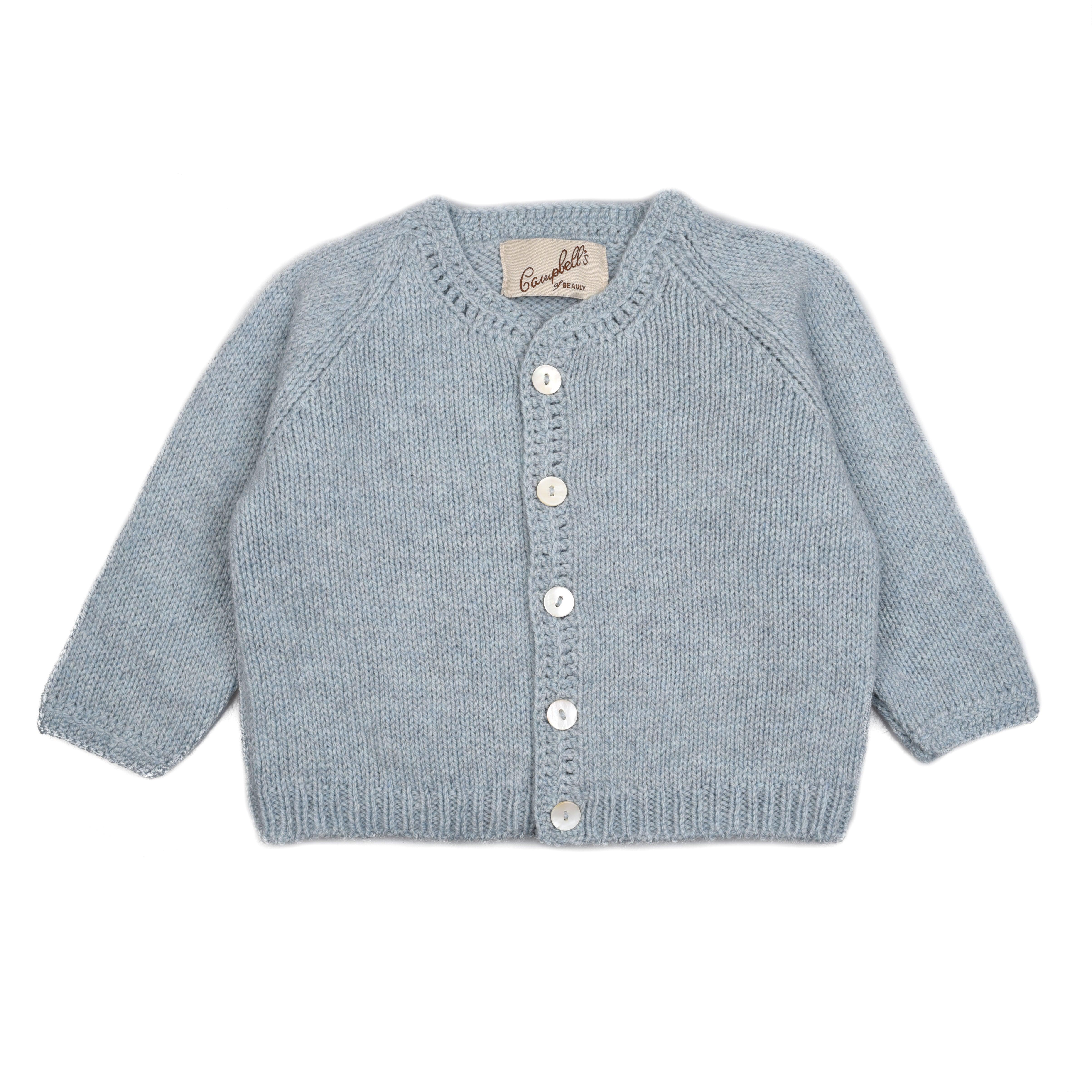 The Campbells of Beauly Baby Cardigan is hand-knitted in light blue superfine lambswool with long sleeves, white front buttons, a round neckline, soft texture, traditional silhouette, and a cloth tag inside the neck.