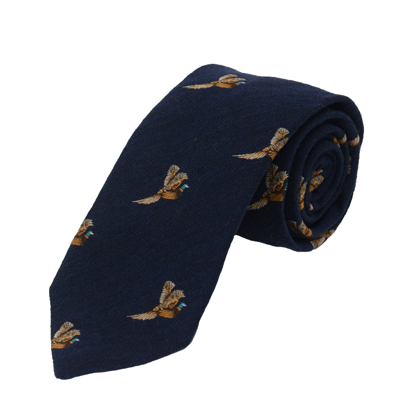 The Campbells of Beauly Pheasant In Flight Silk Tie, in navy blue, features embroidered brown and tan pheasants in flight, evenly spaced across the handmade fabric. The tie is shown rolled on a plain white background.
