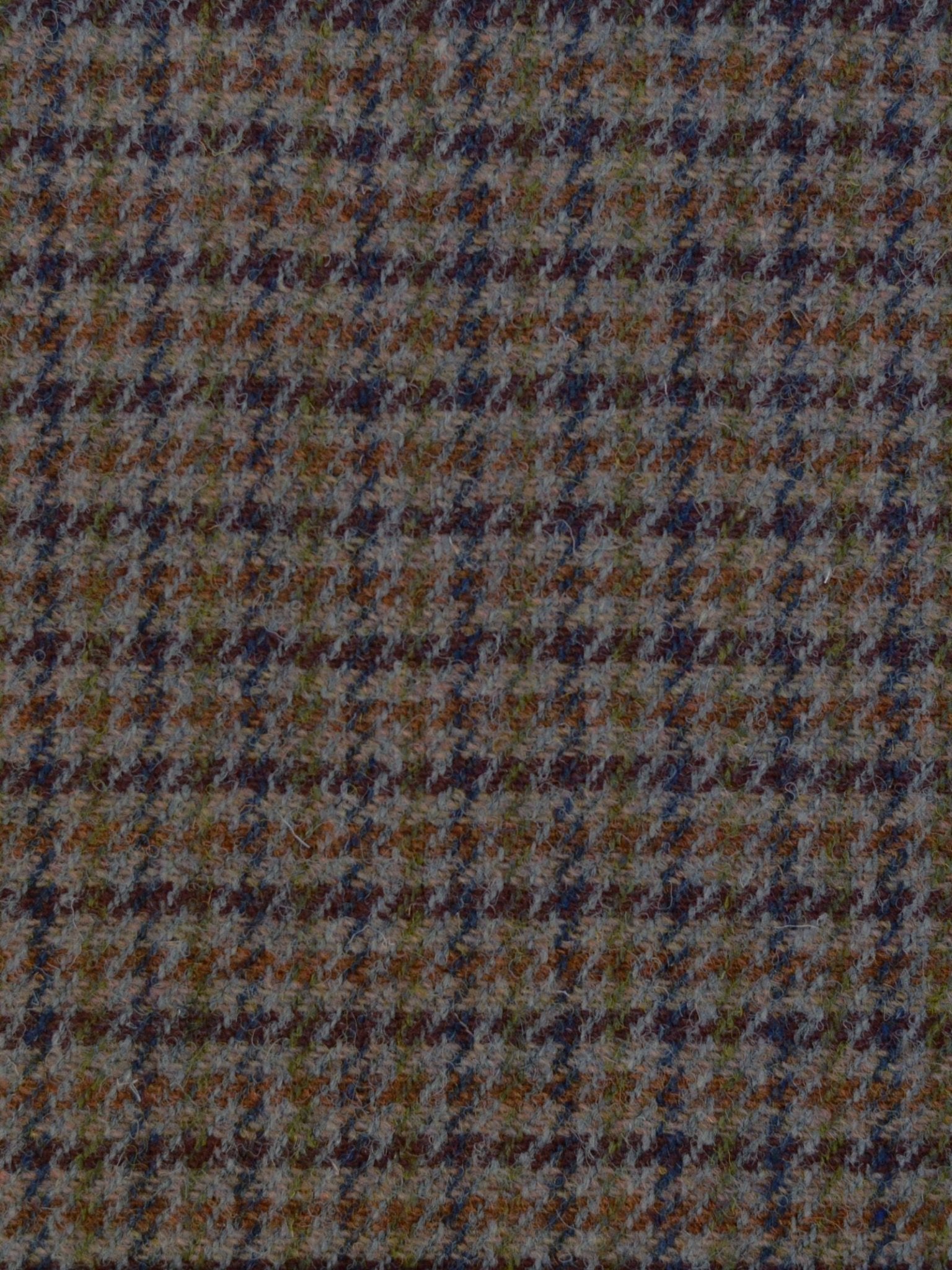 A close-up of Campbell's of Beauly House Tweed 93914: a Harris Tweed wool fabric in muted brown, blue, olive green, and orange houndstooth, showcasing classic Scottish weaving and timeless texture.