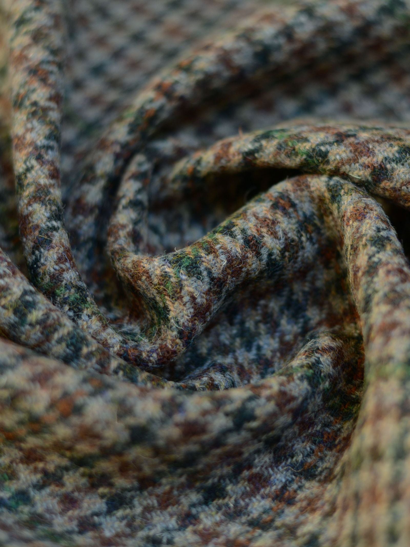 A close-up of Campbell's of Beauly House Tweed 93900 fabric, featuring soft, woolen texture with multicolored patterns and folds in brown, blue, green, and gray shades.