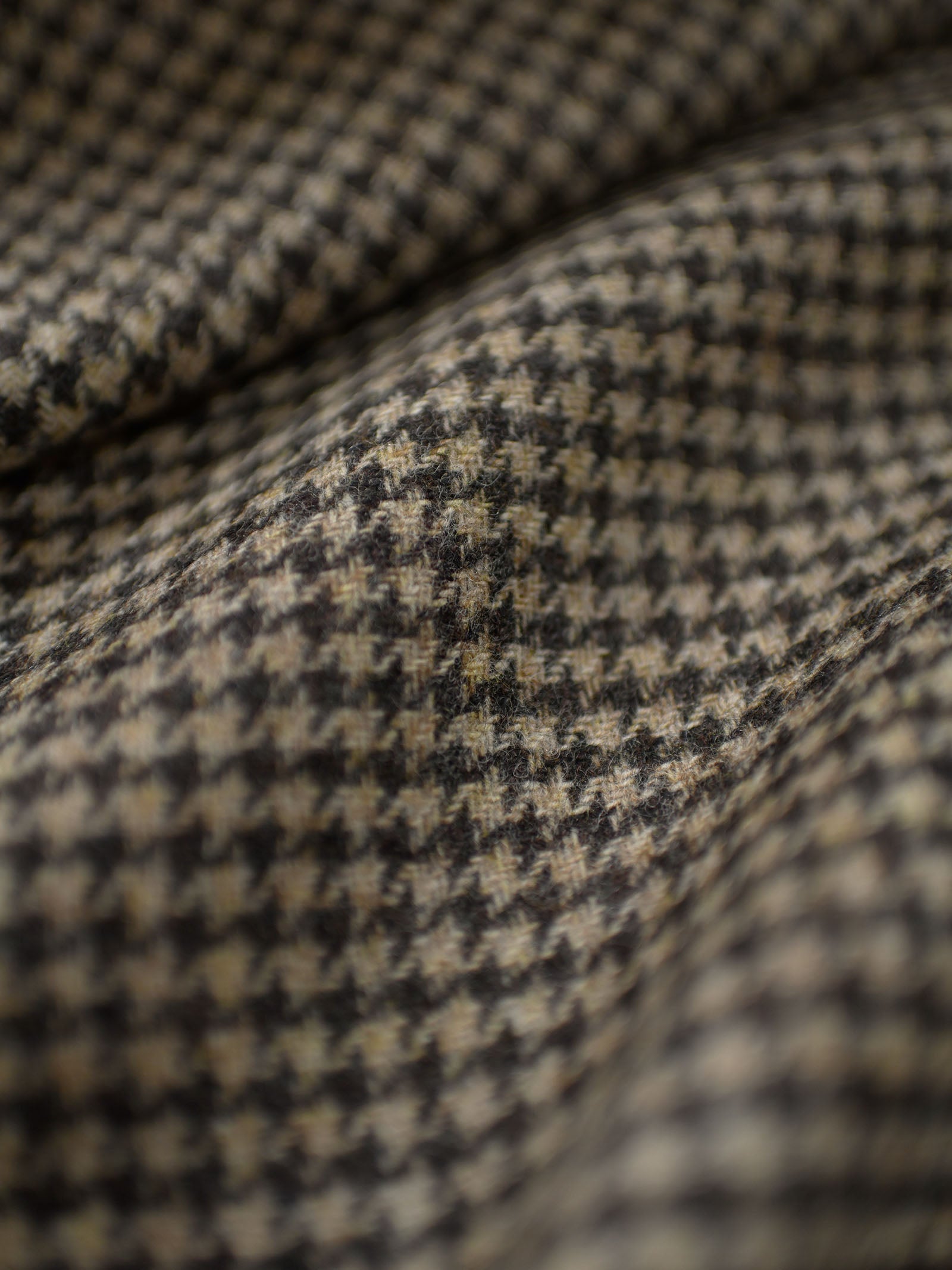 Close-up of Campbell's of Beauly House Tweed 83654, featuring a classic black and beige houndstooth pattern in 100% wool Shetland Tweed, highlighting the detailed texture and soft folds of this premium jacketing fabric.