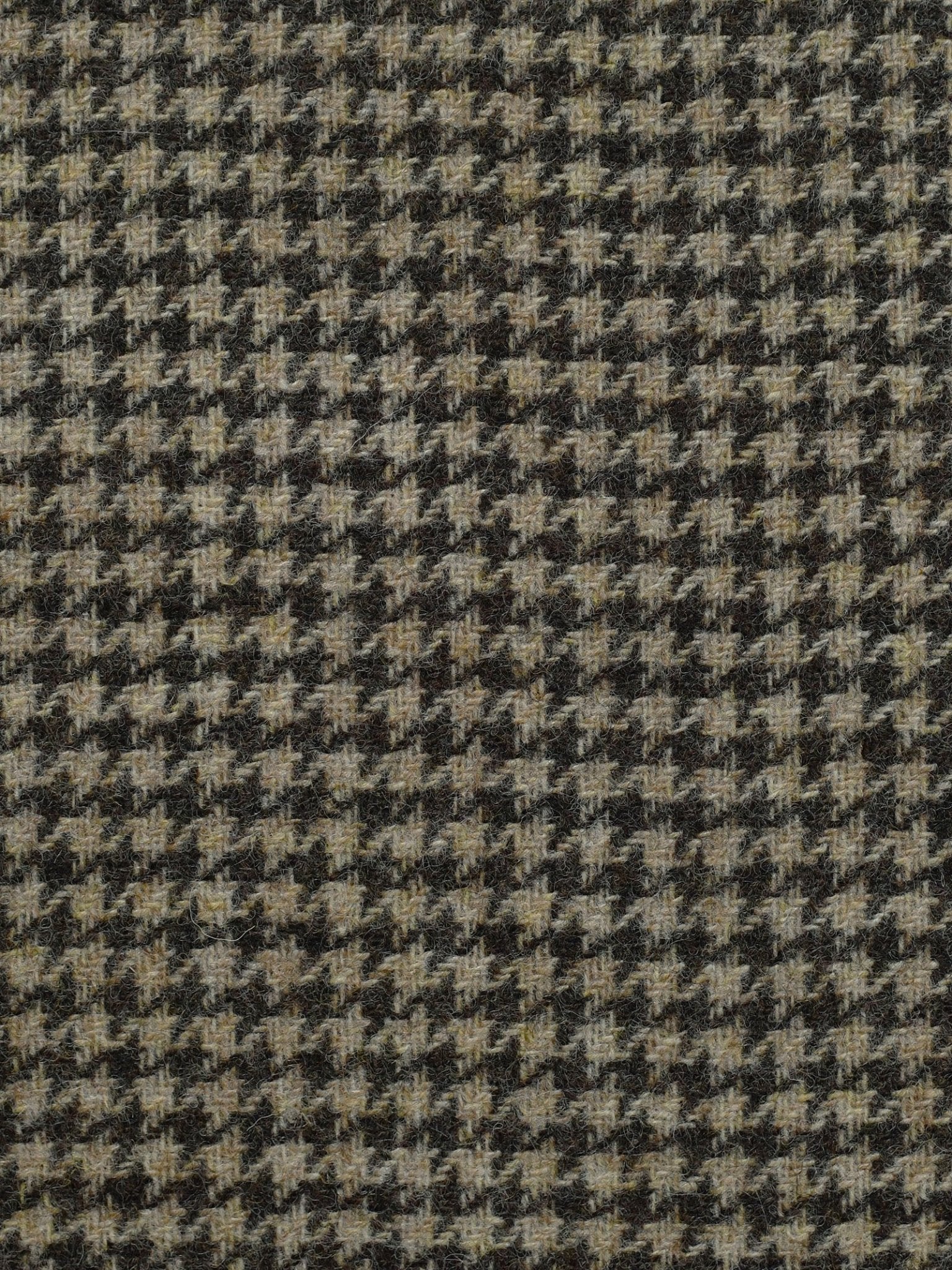 Close-up of Campbell's of Beauly House Tweed 83654, a 100% wool Shetland jacketing fabric in black, gray, and beige houndstooth, showcasing the classic repeating broken check design.