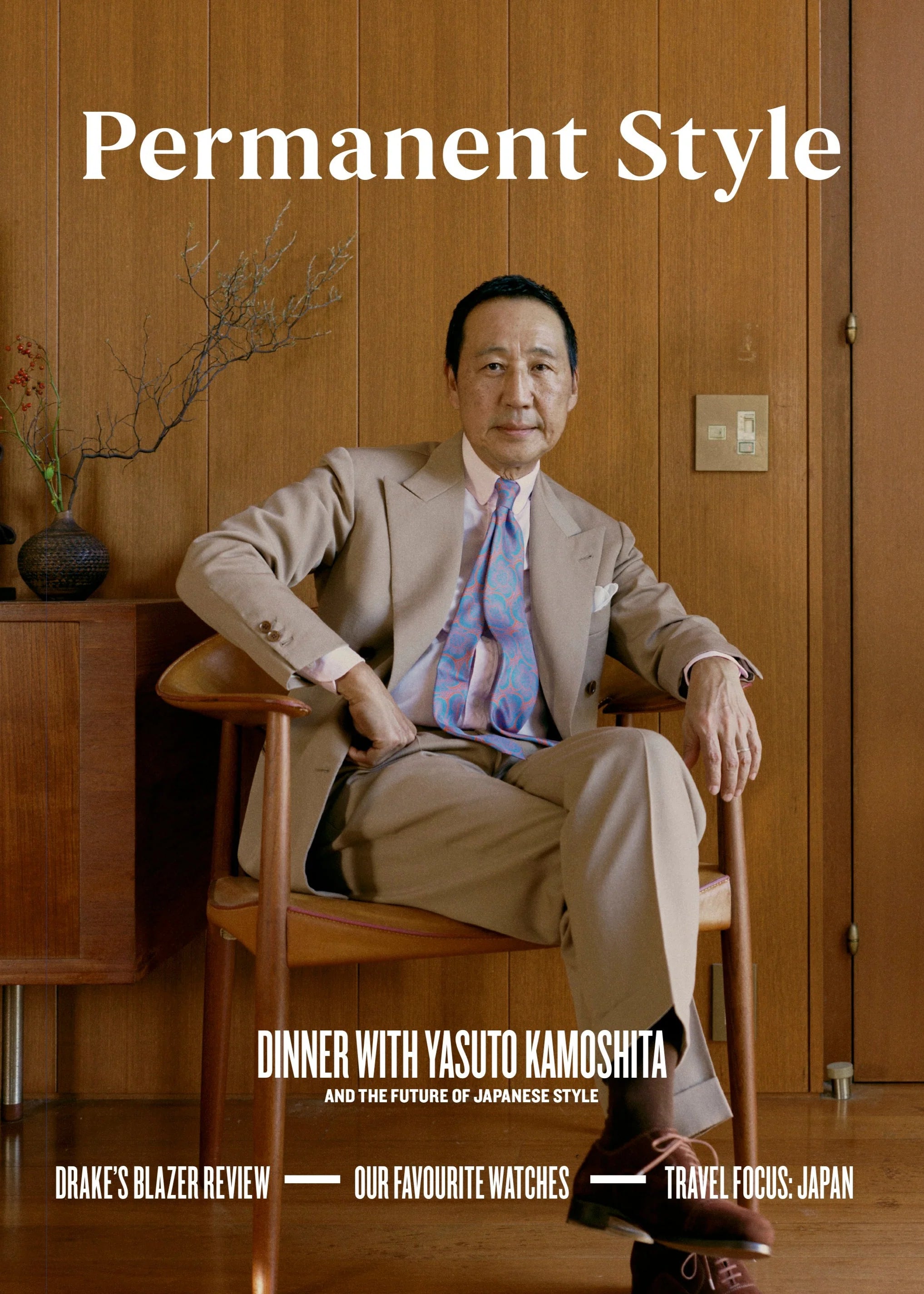A well-dressed man in a tan suit with a colorful tie sits in a stylish, wood-paneled room. “Permanent Style Magazine” by Permanent Style features Yasuto Kamoshita, Drake’s blazer review, watches, and a Tokyo shopping guide.