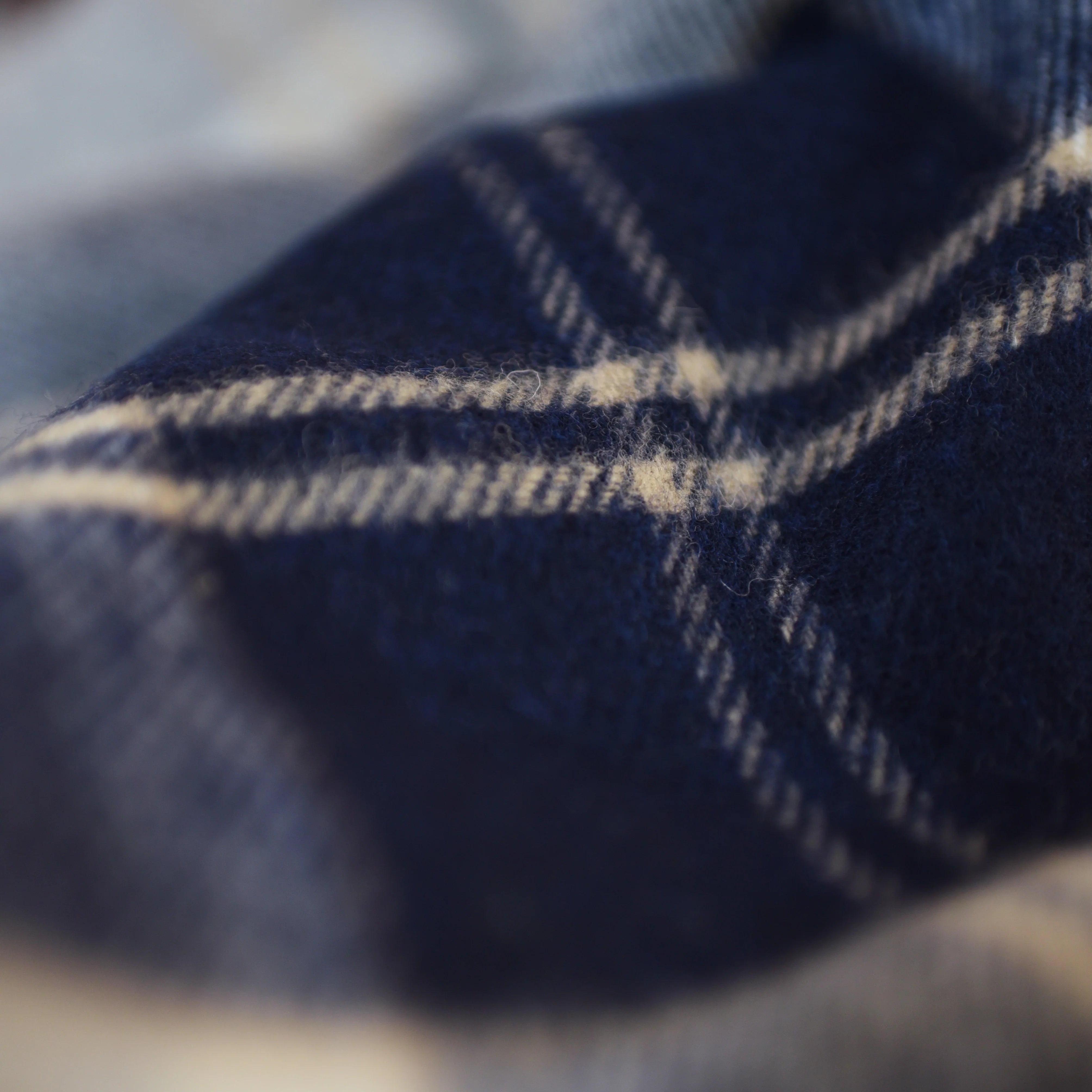 Close-up of the Lambswool Tartan Blanket by Campbell's of Beauly, highlighting its soft blue and white intersecting lines and textured lambswool surface that evoke warmth and cozy comfort.