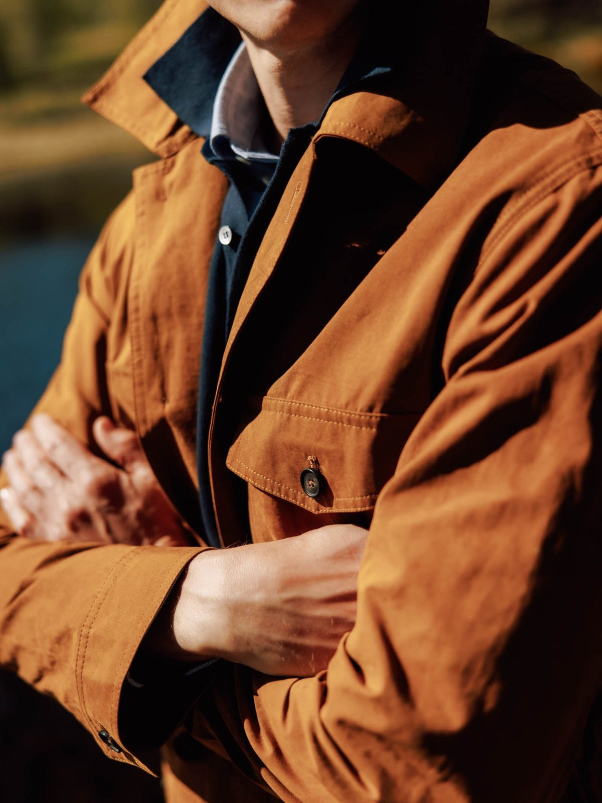 A tan Campbell’s of Beauly Aigas Field Jacket in water-repellent peach skin fabric worn over a dark blue shirt with arms crossed.
