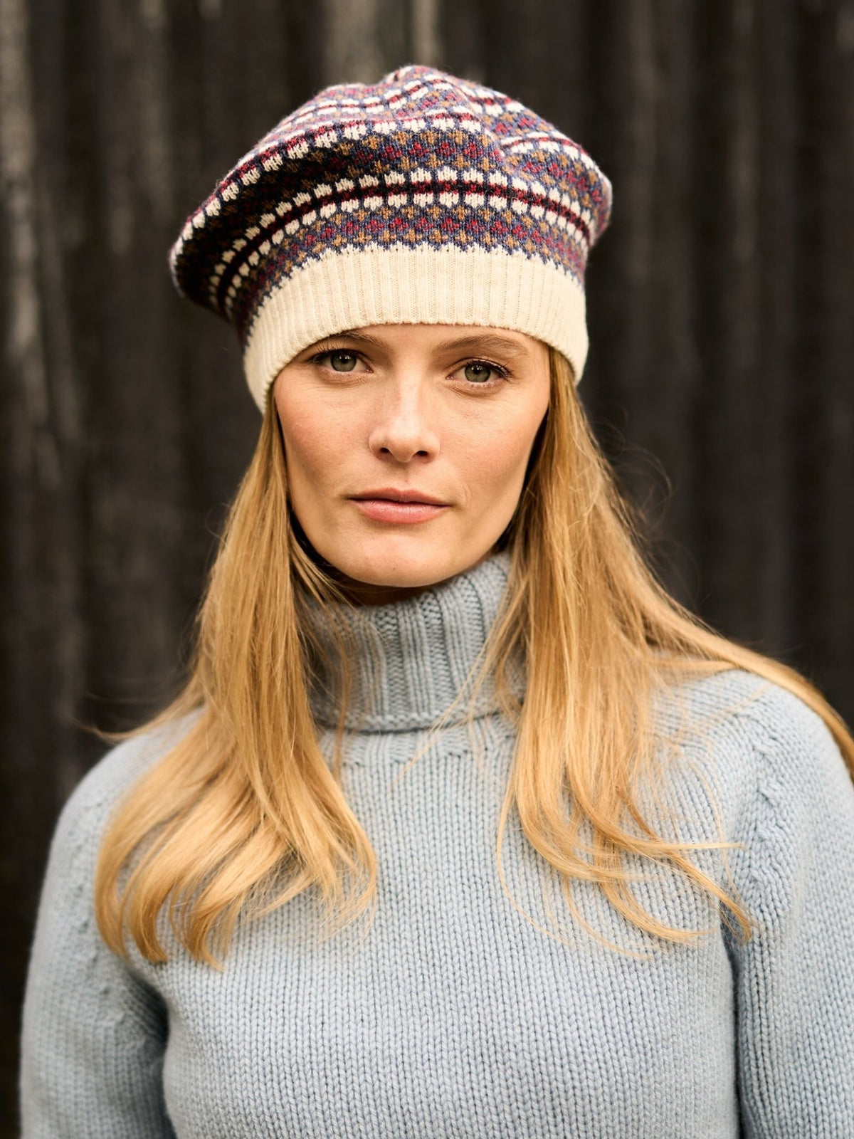 A woman wearing a cream-colored Campbell’s of Beauly Lambswool Fairisle Beret with a multi-colored design.