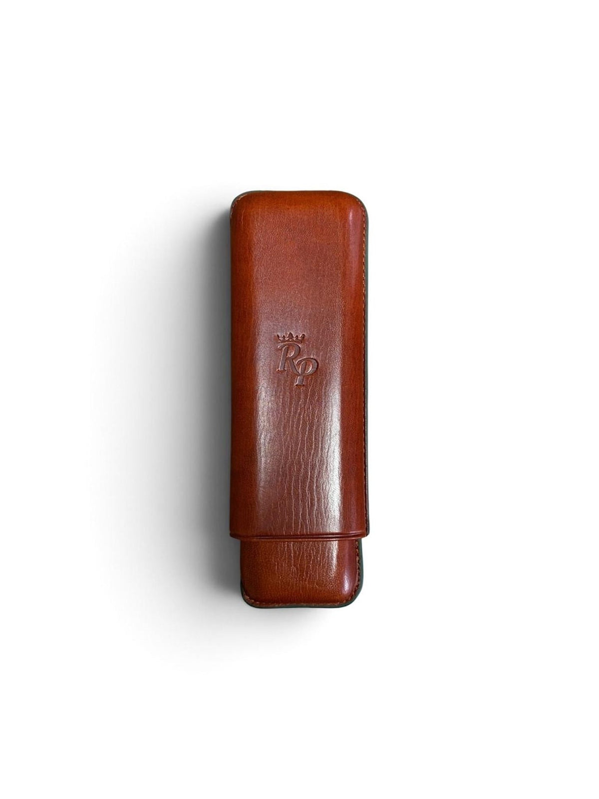 Introducing the Rey Pavón Leather Cigar Case—a brown leather accessory with a protective flap and an embossed Rp logo at its center. Captured against a white backdrop, this tubular case blends sophistication and practicality, making it an essential protector for any discerning cigar aficionado.
