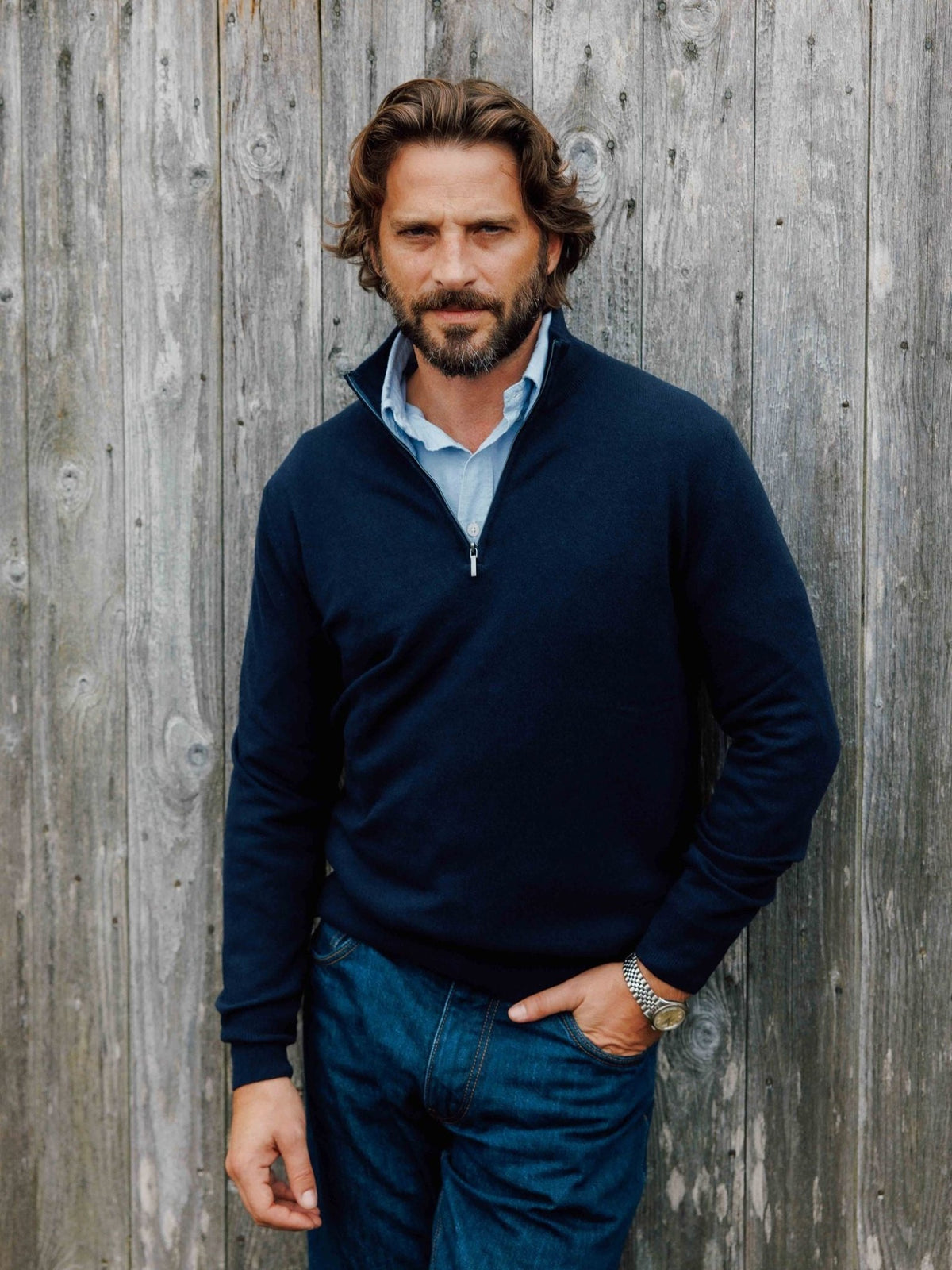 A man wearing a navy blue Campbell’s of Beauly Merino & Cashmere Quarter Zip Jumper over a light blue collared shirt.