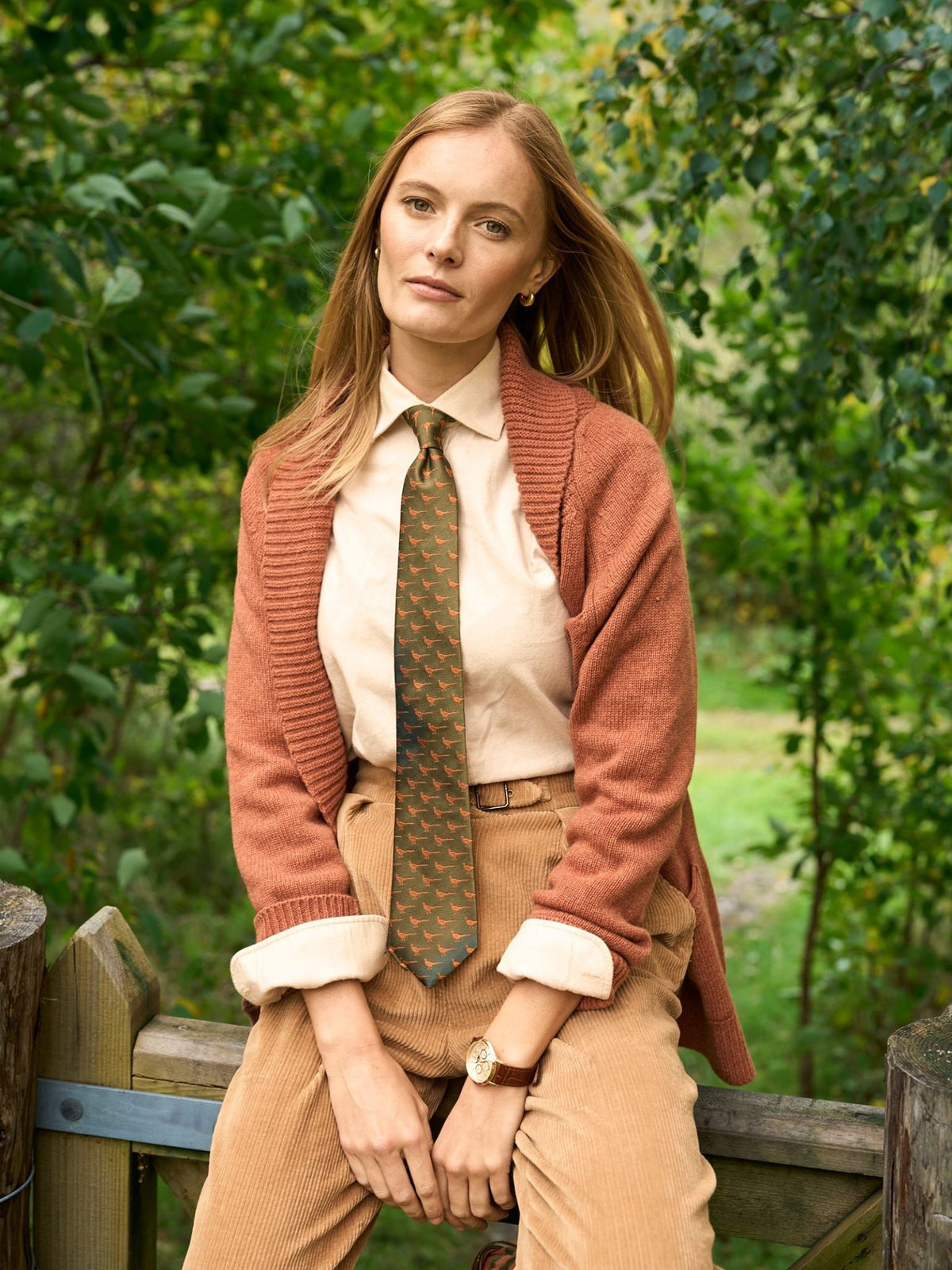 A person wearing a light tan collared shirt, a rust-colored cardigan, and a Campbell’s of Beauly Pheasant Silk Tie in dark green.