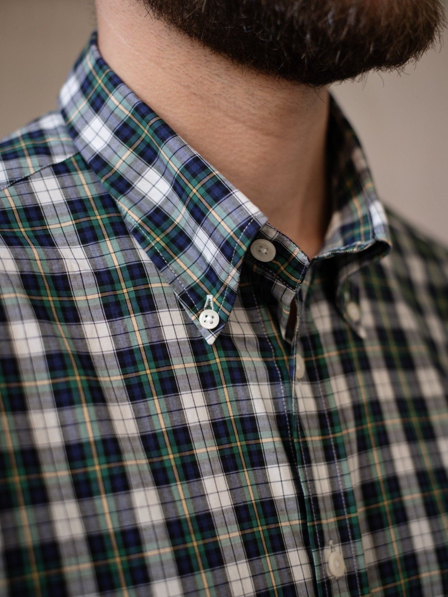 A bearded person wears a Campbell's of Beauly Cotton Tartan Button Down Shirt in blue, green, and white plaid. The image shows the lower face, neck, and upper chest.